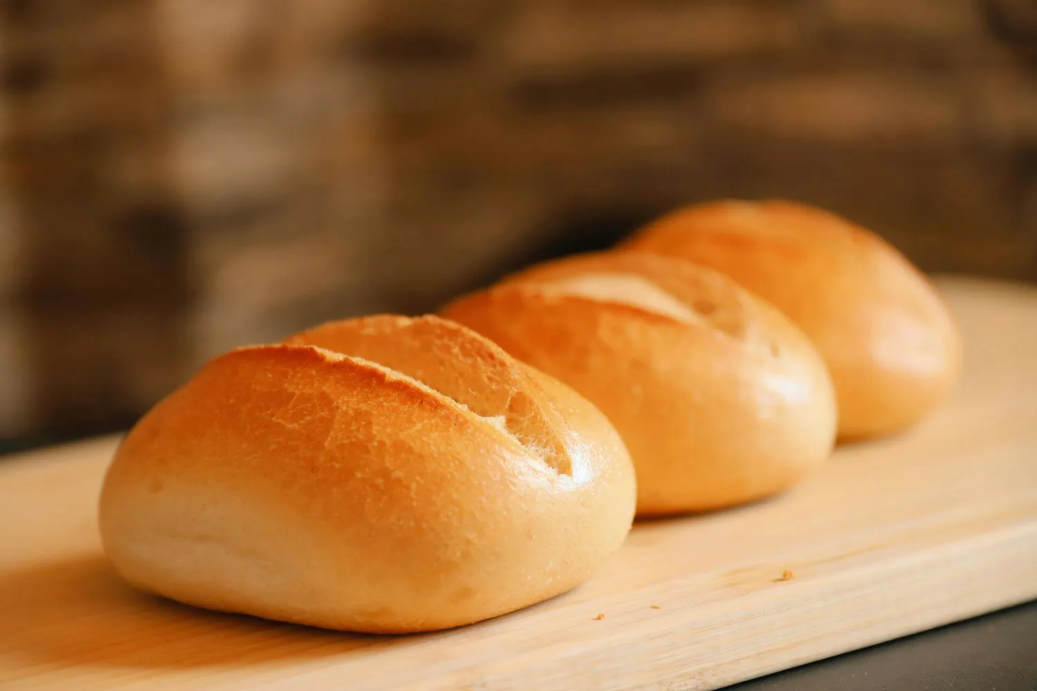 Three freshly baked bread rolls on a board at Dragon Bay Bakery, a Chinese Bakery in Brooklyn
